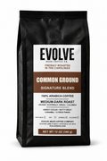  12 oz black bag of Evolve Bean Coffee Company Common Ground Signature Blend medium-dark roast coffee on a white background.