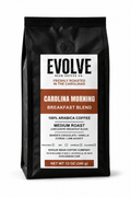 A 12 oz black bag of Evolve Bean Coffee Co. Carolina Morning Blend medium roast coffee, featuring a white and brown label on a clean white background.